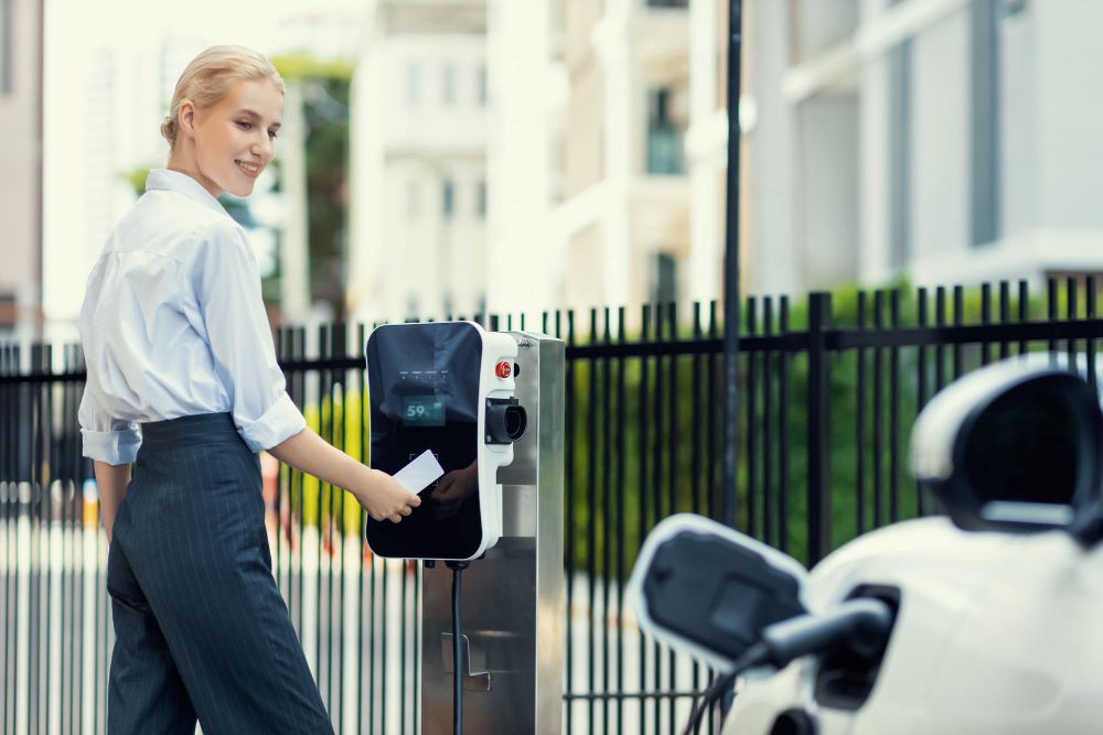 kobieta płacąca za ładowanie auta elektrycznego

